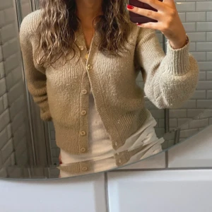 Beige stickad kofta med knappar - Mysig beige stickad kofta med långa ärmar och knappar framtill. Den har lite guldigt glitter i sig! 💕