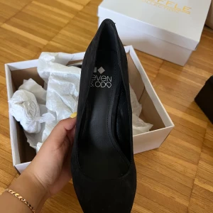 Svarta pumps med hög klack från Even&Odd - Säljer ett par svarta pumps från Even&Odd med hög klack och plattform. Skorna har en spetsig tå och är tillverkade i ett material som ser ut som mocka. 