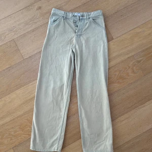 Beige raka byxor från Filippa K - Snygga beige byxor från Filippa K med raka ben och klassisk passform. Byxorna har knäppning med knappar framtill och är tillverkade i ett mjukt bomullsmaterial. Perfekta för en stilren och avslappnad look.