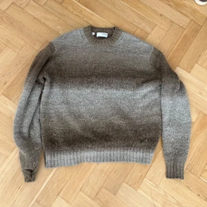 Stickad tröja  - Säljer en gråmelerad stickad tröja från Selected HOMME. Tröjan har rund halsringning, långa ärmar och ribbade muddar vid ärmslut och nederkant. Perfekt för kyligare dagar och enkel att matcha med jeans eller chinos.