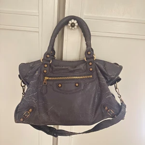Balenciaga city bag - Supercool city bag från Balenciaga i en unik blå/lila färg🙌🏼 väskan är köpt från Vestiaire collective för ca 7000kr! Den är väldigt sliten och har varit hos skräddaren 1 gång (se bild på axelband och vid dragkedjan)❤️ Pris går att diskuteras! Önskas orderbevis från Vestiaire kan jag skicka de😊