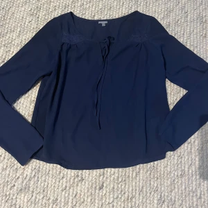 Mörkblå blus med knyt från Charlotte Russe - Säljer en mörkblå blus från Charlotte Russe med långa ärmar och knytning vid halsen. Blusen har en enkel och stilren design. 