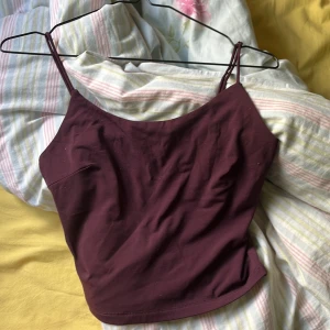 Mörklila linnetopp med smala axelband - Säljer en enkel och stilren mörklila linnetopp med smala axelband. Toppen har en rak passform och är perfekt att matcha med jeans eller kjol. Superenkel att styla för olika tillfällen!