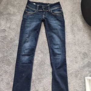 Pepe Jeans straight low waist jeans 25/30 - Mörkblå raka jeans från Pepe Jeans med låg midja och klassiska kontrastsömmar. Modellen heter Venus och har snygga detaljer på bakfickorna. Tillverkade i bomull med lite polyester och elastan för extra komfort.
