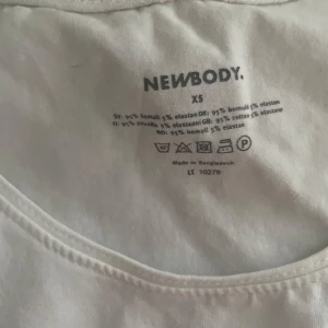 Vit linnetopp från Newbody XS - Klassisk vit linnetopp från Newbody i storlek XS. Toppen är ärmlös med rund halsringning och tillverkad i mjuk bomull med lite stretch för en bekväm passform. Perfekt att bära under skjortor eller som den är under varma dagar.