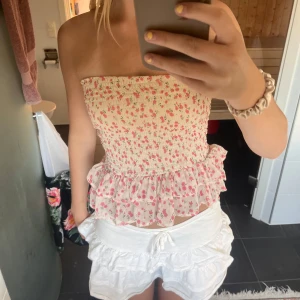 Blommig volangkjol från Bik Bok - Supersöt kort kjol från Bik Bok i ljusbeige med små rosa blommor. Kjolen har smock upptill och dubbla volanger nertill som ger en riktigt gullig och somrig vibe. Perfekt för dig som gillar romantisk stil och vill ha något luftigt och lätt. Funkar även jätte bra att använda dom bandåtopp 🫶🏼