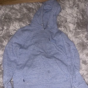 Ljusblå hoodie med huva och ficka - Mysig ljusblå hoodie med stor känguruficka framtill och dragsko i huvan. Tröjan har en relaxed passform och är perfekt för chill dagar. Tillverkad i mjuk bomullsblandning och har långa ärmar.