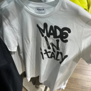 Vit t-shirt Dondup med tryck - Vit t-shirt från Dondup med svart graffiti-inspirerat tryck 'MADE IN ITALY' på bröstet. T shirten är helt ny från butik och är helt slutsåld!