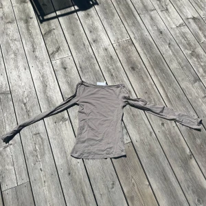Beige långärmad topp från Weekday XS - Säljer en beige långärmad topp från Weekday i storlek XS. Modellen är tight med offshoulder-skärning och tillverkad i mjuk bomull. Perfekt att styla med jeans eller kjol för en clean look.