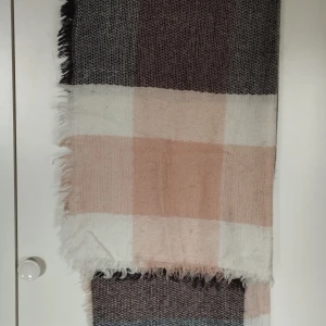 Rutig halsduk - Stor och mysig halsduk med rutigt mönster i beige, svart och vitt. Halsduken har fransar i kanterna och är vävd i ett mjukt material som känns skönt mot huden. Perfekt att svepa runt halsen för extra värme på kvällen. Säg till om du vill ha bild på hela varan; Bilderna beskärs så dumt i appen.