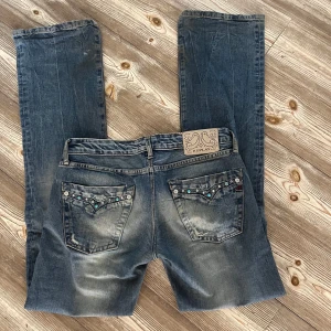 Lågmidjade bootcut jeans från Replay - Snygga blå bootcut jeans från Replay med snygga detaljer på fickorna. Storlek:25/32 Innerbenslängd: 82 Midjemått: 35