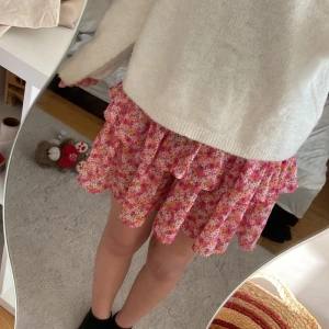 Blommig volangkjol från ONLY S - Supersöt kort kjol från ONLY med blommigt mönster i rosa, vitt och orange. Kjolen har volanger och en flowy passform som ger en lekfull vibe. Perfekt för dig som gillar färg och vill sticka ut lite extra i sommar eller vår.
