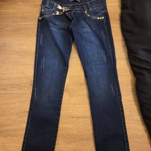 Mörkblå skinny jeans med leopardbälte - Snygga mörkblå skinny jeans med coola slitningar och dekorativa nitar på fickorna. Byxorna har ett leopardmönstrat bälte och kontrastsömmar på bakfickorna. Perfekta för dig som gillar detaljer och en smal passform.