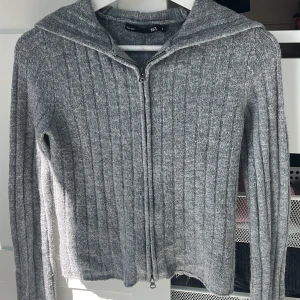 Grå ribbad hoodie med dragkedja 157 - Grå ribbstickad hoodie från 157 med huva och hel dragkedja framtill. Tröjan är långärmad och har en klassisk, enkel look som passar till många outfits. Jag älskar verkligen den här tröjan! ❤️