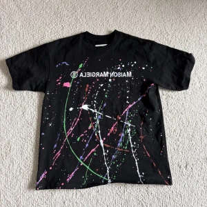 Maison margiela T-shirt - Säljer denna as feta t-shirten med färgstänk från Maison Margiela! Den är i storlek M!( Lite stor i storleken!) Säljes för 400! Pris ej hugget i sten! Hör av dig vid frågor och funderingar!!