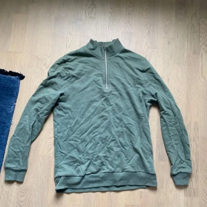 Grön half zip tröja - Snygg grön långärmad tröja med half zip-dragkedja i halsen. Tröjan har en hög krage och är tillverkad i mjuk bomull. Perfekt för lager-på-lager och chill dagar. Enkel och stilren design som funkar till det mesta.