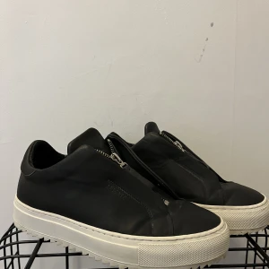 Arigato clean 90 zip sneaker  - Svarta arigato skor i storlek 37, fint skick! Originalpris 2250, säljs inte längre med denna typ av taggig sula!   Föredrar upphämtning/träff men går även att frakta (frakten betalas av köpare)