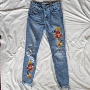 Jeans från Zara - Ett par jeans med broderade blommor på i superskick från Zara Trafaluc i storlek 32. För mer frågor och bilder är det bara att höra av dig!