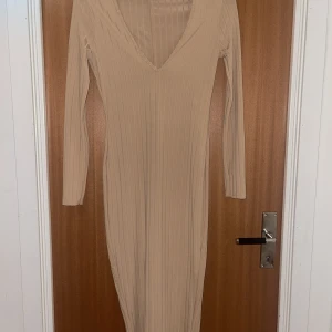 Maxiklänning - En lång beige färgad klänning med slitsad bak. Använd endast ett tillfälle