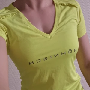 Gul träningstopp  - Träningstopp från Röhnish i funktionsmaterial. Oanvänd så mycket fint skick. Säljes pga garderobsrensning 