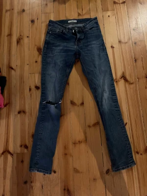 Blå jeans - Blå jeans från Cubus med hål vid knät. Namnat. Bra skick. Djur i hemmet.