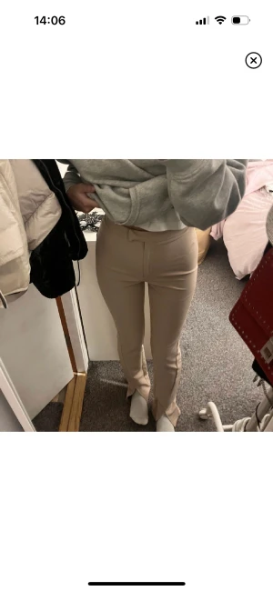 Kostymbyxor med slits  - Ett par beige kostymbyxor med slits där nere. Köpt ifrån nakd men har endast kommit till användning en gång. Storlek 32 men passar mig som bruka ha 34.