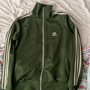 Adidas tröja grön och beige - En enkel adidas tröja i grönt och beige. Storlek M men kort i längden hade sagt att den passar folk från 160-170 köparen står för frakt