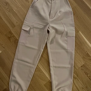 Cargobyxor Beige - Beiga cargobyxor, små i midjan. Passar XS.