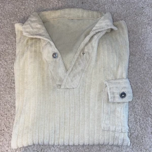 T-shirt med krage - Mjuk T-shirt i typ frotté? Köpt second hand. Ficka på framsidan och en knapp vid kragen 