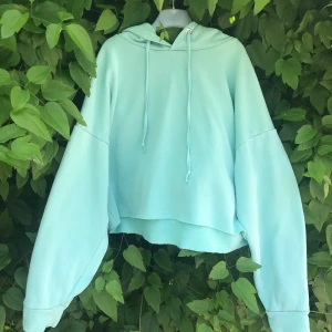 Turkos hoodie  - Ljusgrön hoodie med ”avklippt” kant. Kom så som köpt. Väldigt fint skick! Skön att ha på sig. 