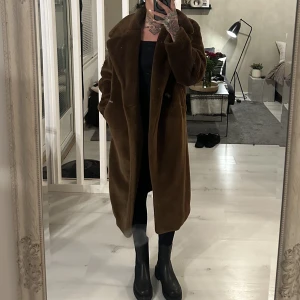 Brun pälskappa från H&M trend  - Har rensat mina ytterkläder - säljer en hel del.  En brun pälskappa från H&M Trend, inköpt för 3 år sen för 1299:-. Använd endast 2 gånger. Jag är 172 cm, och kappan når mina knän i längd. Kappan är i storlek 36, men passade mig när jag var storlek 40-42.