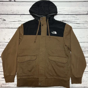 The North Face Jacka/Hoodie - Märke: The North Face  Typ: Jacka/Hoodie  Färg: Brun/Svart  Kroppstyp: Unisex  Skick: Mycket Bra     Sparande av miljö  29x lägre utsläpp jämfört med ny vara  Sparat vatten ca 300 liter  Sparat CO2 ca 6.5 kg