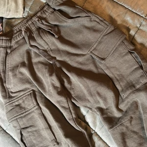 Pocket pants i bomull  - Pocket pants med stora fickor, snören och uddar nere på benen. Är en finare grön färg i verkligheten! Har inte använt alls mycket men de blev lite noppriga efter första tvätten. Men det syns inte på håll! FRAKTEN ÄR EJ KOREKT. ⚠️