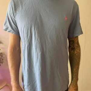 Ljusblå polo t-shirt  - T-shirt med extra för den som vill ha den. Size L jag är 183 cm. Hästklubbmannen är broderad i rosa vilket va fett metro 2000. 