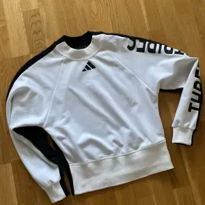 Adidas tröja som aldrig är använd. Den är vit på framsidan och svart på baksidan. Tröjan har ett tryck på ärmen. Storlek xs 
