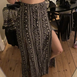 Lång kjol - Lång, high-waisted kjol med coolt mönster och snittar vid låren. Använd en gång. Storlek XS.