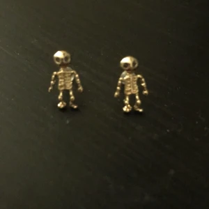 Ett par döskall örhängen  - Ett par örhängen som har guldiga döskallar