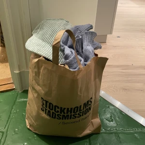 Klädpåse  - Tänkte börja med klädpåse igen, va mkt uppskattat senast. Bygger på spontanköp å känsla för det lilla som syns. Kommer med utöver keps å lila väst även två klänningar med spetsdetaljer, en svart å en rosa. Beiga tights till träning med detaljer å Leotröja