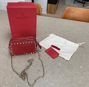 Valentino Garavani clutch bag - Äkta Valentino Garavani clutch bag i vinrött läder med guldkedja❤️ Köpt på Vestiaire men är i toppskick, ytterst liten repa på framsidan. Korthållare på insidan. Box och extranitar medföljer. Äkthet garanteras!
