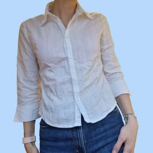 Y2K skjorta  - Vit skjorta som passar in i stilen "Y2K". Skjortan är npgot veoppad i längden så passar bra till ett öar lågmindjade byxor. Den saknar lapp för mårke och storlek men skulle gissa att den är storlek S. Jag själv bär S och 170cm lång,