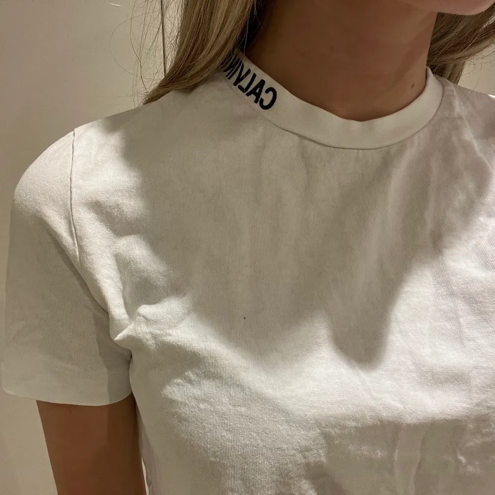Kortare t-shirt från Calvin Klein med coolt logo tryck vid halva halsen i storlek XS🤍. T-shirts.