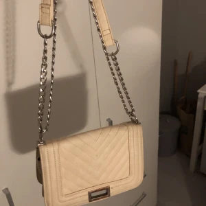 Väska - En beige väska med silver kedja, köpt second hand så är mycket använd💗 köparen står för frakten😊🚚