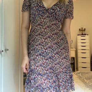 Blommig klänning - Jättesöt blommig klänning. Spänns in med ett band så kan stylas på olika sätt 