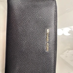 Plånbok från Michael Kors - Större plånbok från Michael Kors med bra utrymme för kort och allt annat man kan tänkas behövas. 