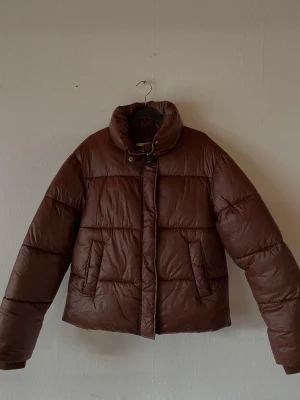 Brun pufferjacket - Säljer en brun puffer jacka från Nelly, strl 38. Använd några enstaka gånger bara. Nypris 699 kr 