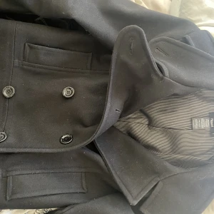 Filippa K ytterkappa - En fin svart ytterkappa från Filippa k i storlek S. Knäpps med knappar framtill. Fickor i sidan. Fint använt skick. 