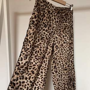 Byxor från ZARA med leopardmönster, vida utsvänga ben med och fickor. Material: Polyester. Utan anmärkningar. Aldrig använda.