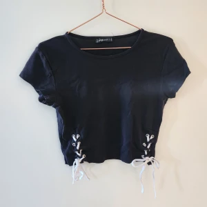 T-shirt med knytdetalj - T-shirt med knytning i sidorna. Säljes pga kommer inte till användning. Hör av dig om du har frågor