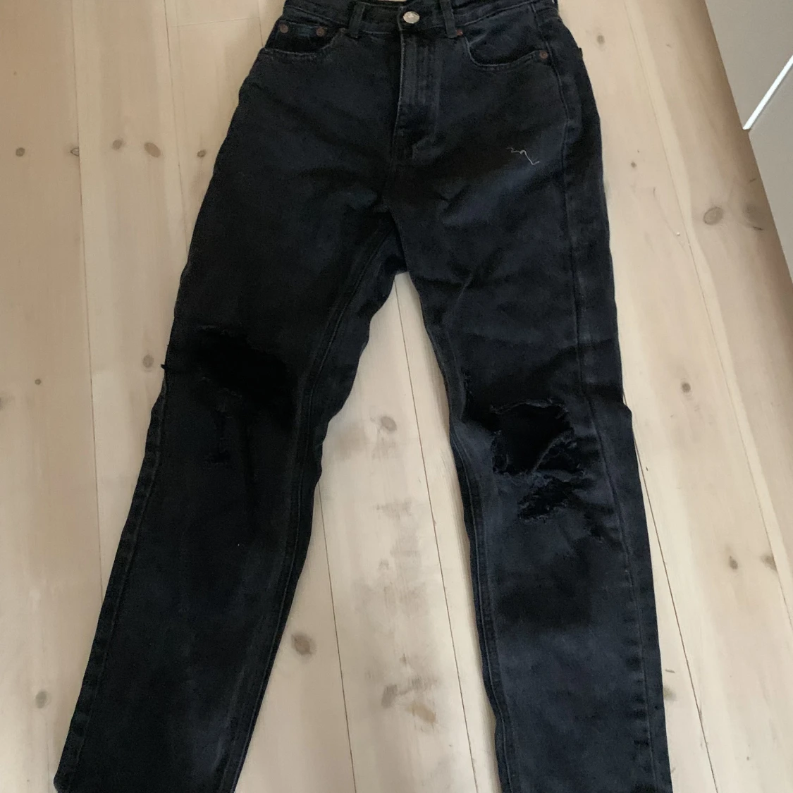 Svarta jeans med hål på knäna