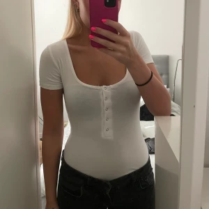 Vit T-shirt body med knappar XS - Vit t-shirt body med knappar, storlek XS